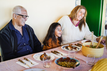 Happy grandparents eating with grand-daughter at home patio - Family moments and food concept -...