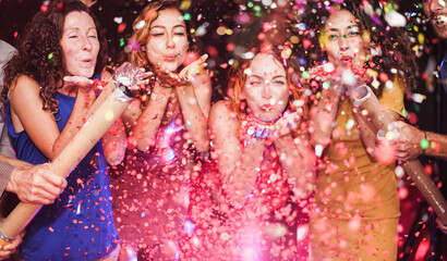 Happy friends celebrating with confetti new year's eve inside disco club - Party concept - Soft...