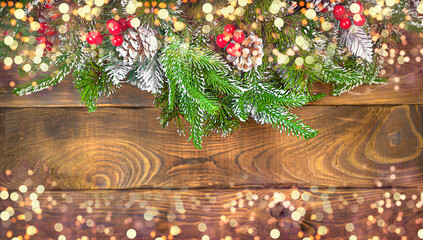 Fototapeta na wymiar Christmas atmospheric card with copy space, with christmas fir branch decorated with bells, lollipops, toys with lights on wooden brown background
