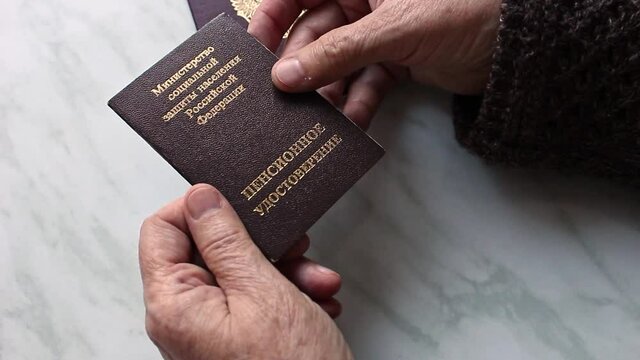 Woman's hand holding russian pension certificate. Russian translation - Ministry of Social Protection of Population of Russian Federation. Pension Certificate.