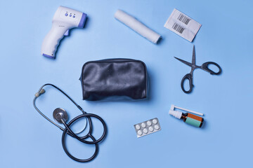 Medical background with various items on blue background. First aid kit package with medial supplies. Infrared thermometer, stethoscope, bandage and medical bag