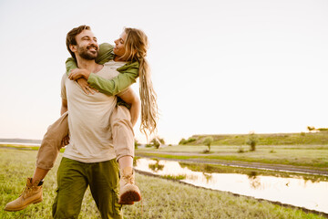 White couple smiling and piggybacking during hiking together