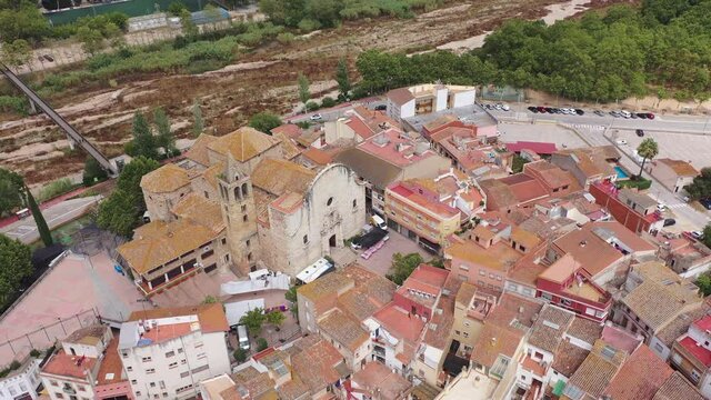 Aerial view of Tordera cityscape with terracotta tiled roofs of residential buildings and parish church of Sant Esteve with Romanesque bell tower on sunny summer day, Catalonia, Spain . 