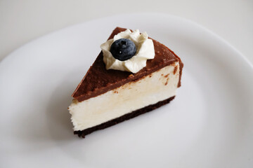 Slice of Pigeon's milk cake on white plate. Chocolate, blueberry, cream