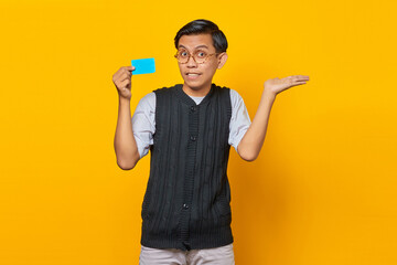 Portrait of smiling handsome young man showing copy space in palm and holding credit card