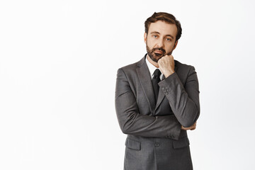 Sad and indifferent corporate man in suit, looking with boredom at camera, lean head on hand, staring reluctant and upset, white background