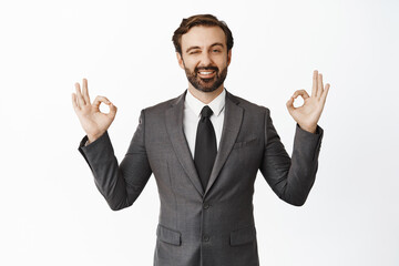 Business people. Handsome male entrepreneur, ceo showing okay signs and winking, smiling pleased, recommending company service, white background