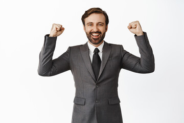 We did it, hooray. Smiling pleased corporate man rejoicing, raising hands up in winner pose, victory, satisfied with great result, white background