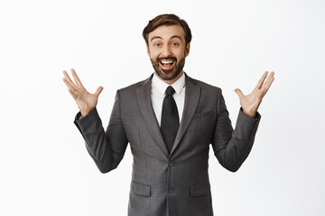 Portrait of enthusiastic salesman celebrating, looking happy and amazed, cheering from great news, achieve goal or win, triumphing, standing over white background