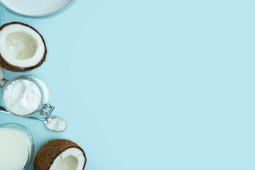 Coconut products. Cracked open coconut with meat cut in half, coconut powder in a glass jar, plant milk on a blue background. isometric projection. Copy space. Concept alternative milk, vegeterian