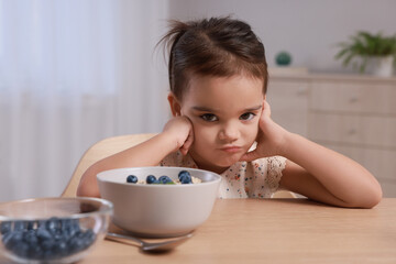 Cute little girl refusing to eat her breakfast at home