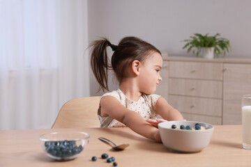 Cute little girl refusing to eat her breakfast at home