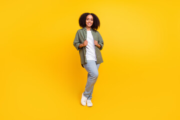 Fototapeta na wymiar Full size photo of lovely brunette young curvy lady stand wear shirt jeans sneakers isolated on yellow color background