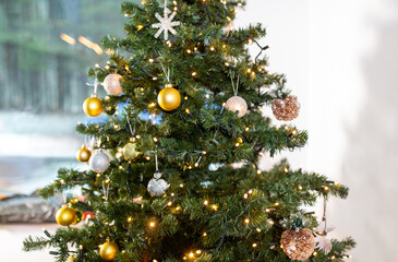 winter holidays, new year and celebration concept - close up of green artificial christmas tree decorated with toys at home
