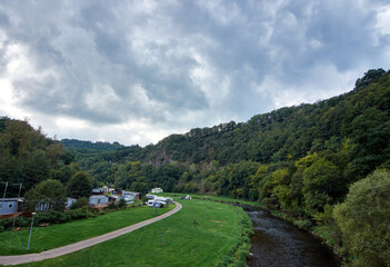 A mesmerizing shot of a landscape with a river surrounded by the green forest, Luxembourg