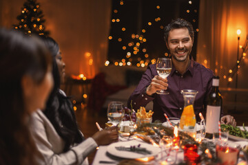 holidays and celebration concept - happy friends having christmas dinner at home and drinking red wine