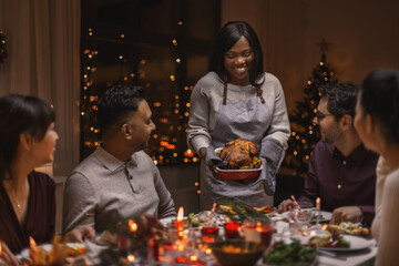 holidays and celebration concept - multiethnic group of happy friends having christmas dinner at home