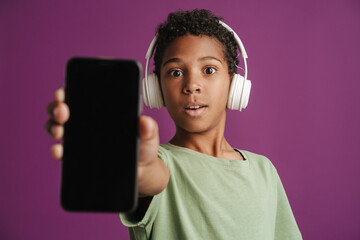 Black boy wearing headphones while showing his mobile phone