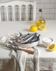 fresh raw fish, Garfish, sardines with lemon and salt on kitchen, close up modern shot, harsh sun light