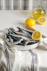 fresh raw fish, Garfish, sardines with lemon and salt on kitchen, close up modern shot, harsh sun light