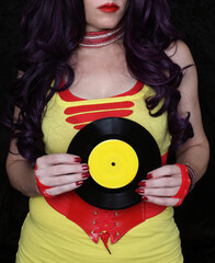 Woman in 1980s yellow clothing holding 45rpm record. Record label painted with yellow poster paint