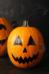 Pumpkins with drawn spooky faces on dark background. Halloween celebration