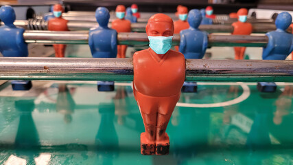 Conceptual covid image: table soccer player wearing masks to protect from coronavirus Covid 19 pandemic