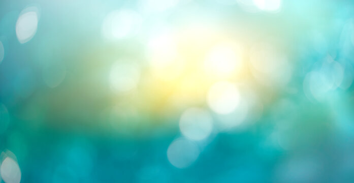A winter abstract sky background with cold wintery blue and sunshine yellow bokeh sparkling sun in the centre.