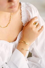 Close-up of female hands and neck with gold jewelry, white shirt