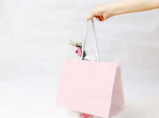 Hand holding a pink gift paper bag with pink flower