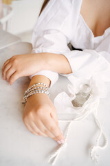 Obraz na płótnie Canvas Women's hands with a silver bracelet beautifully hold perfume
