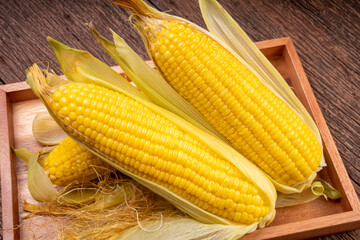 Sweetcorn in wooden plate on wooden background, Corn on a wooden table background.