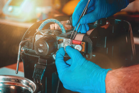 A repairman repairs a broken coffee maker