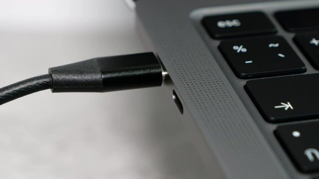Close up woman hand plug in USB type C cable into the port on laptop for charging the power