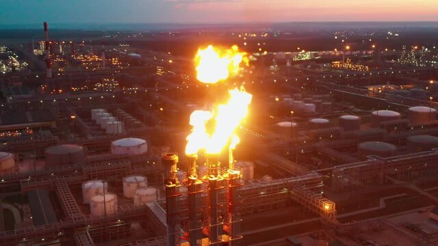 Refinery flare stacks are releasing flashes of fire in the evening