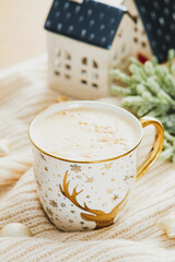Hot cappuccino mug with christmas decoration on knitted plaid.