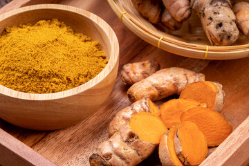 Turmeric Powder and Turmeric root in wooden plate, Curry Powder on a wooden table background.