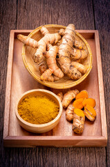 Turmeric Powder and Turmeric root in wooden plate, Curry Powder on a wooden table background.