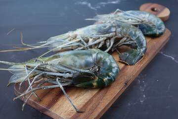 close up of king prawn on a chopping board on table.