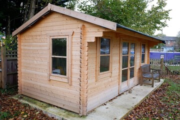 Fototapeta na wymiar Wooden summer house or pine log cabin on concrete base with felt roof
