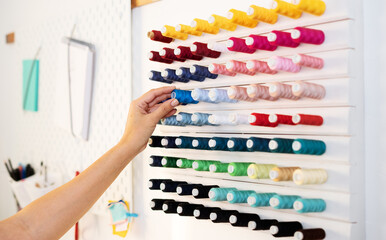 A girl tailor selects colored threads for tailor job. Close-up of hands
