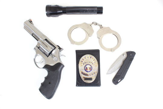 Handgun With Security Badge and Handcuffs on White Background