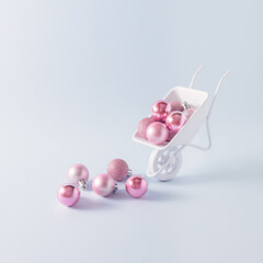 Creative layout made of white Wheelbarrow and New Year's pink baubles. New Year or Christmas concept.Xmas grounds trolley.