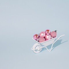 Creative layout made of white Wheelbarrow and New Year's pink baubles. New Year or Christmas concept.Xmas grounds trolley.