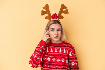 Young caucasian woman wearing a christmas reindeer hat isolated on yellow background showing a disappointment gesture with forefinger.