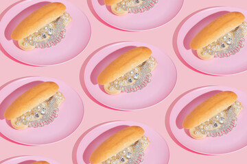 Creative pattern with luxury jewelry in hot dog buns on pink plates on pastel pink background.  80s...
