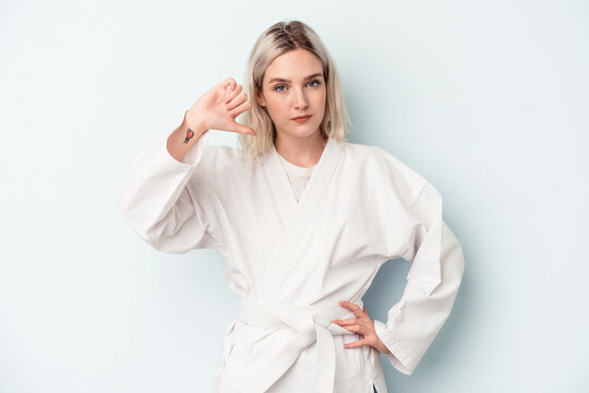 Young caucasian woman doing karate isolated on blue background showing a dislike gesture, thumbs down. Disagreement concept.