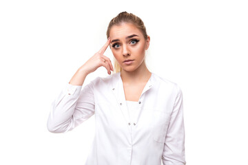 Fototapeta premium Photo of an attractive sad young blonde woman with a ponytail and makeup in a white medical coat of a nurse touches herself with finger isolated on a white background with free and copy space for text