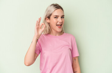 Young caucasian woman isolated on green background cheerful and confident showing ok gesture.