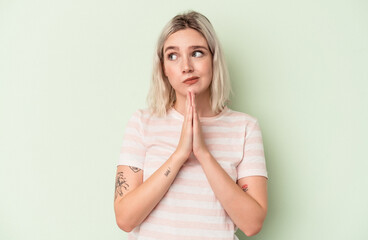 Young caucasian woman isolated on green background praying, showing devotion, religious person...